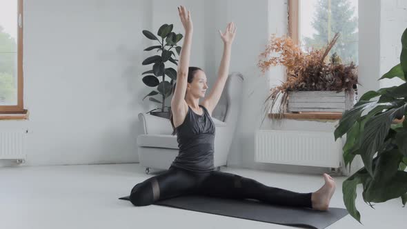 Young Sporty Brunette Girl in Sportswear Does Exercises in Bright Room at Home