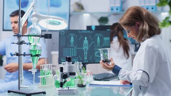 Female Biologist Looking at Plant Samples and Taking Notes alt