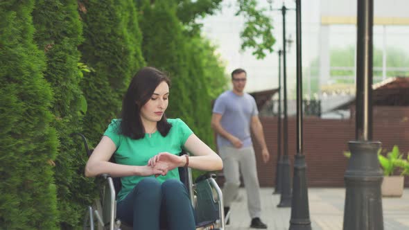 Cute Disabled Girl in a Wheelchair Waiting for Her Friend in the Park