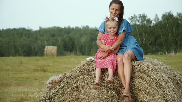 Mother with daugter sitting on haystack