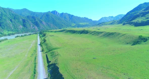 Aerial Rural Mountain Road and Meadow at Sunny Summer Morning. Asphalt Highway and River