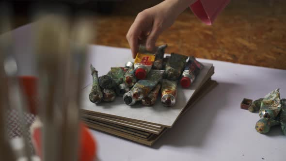 Woman Artist Stacks Used Old Tubes of Paint in a Pile to the Rest