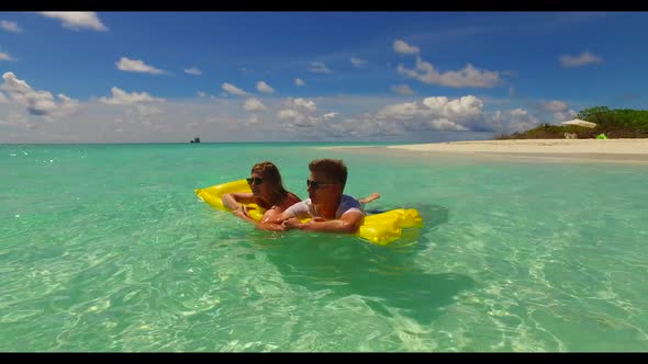 Romantic couple sunbathing on paradise seashore beach holiday by blue sea and white sand background 