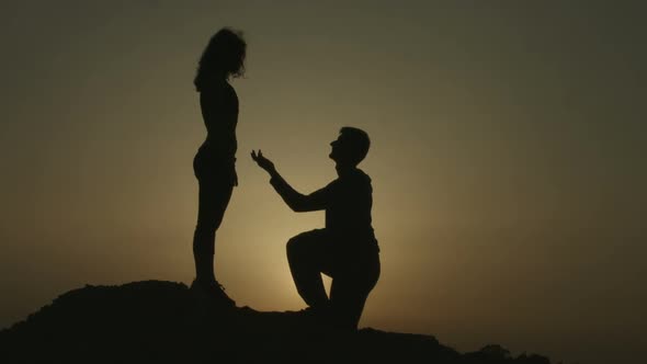 Silhouette of Young Man Proposing to Girlfriend on His Knee, Romantic Engagement