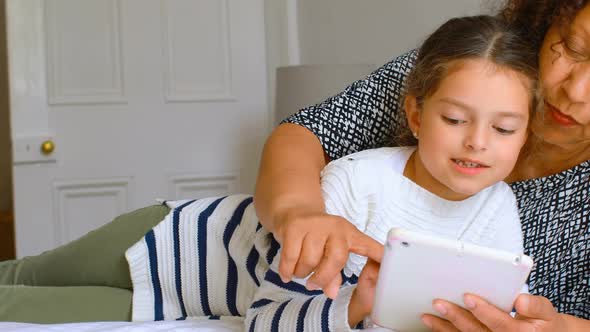 Girl using digital tablet with grandmother in bedroom 4k