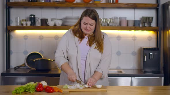 Portrait of Overweight Woman on Diet Crying Chopping Onion in Kitchen