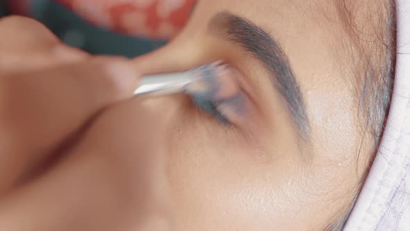 Close up of woman's eye and make up artist putting eye shadow with make up brush on her eye