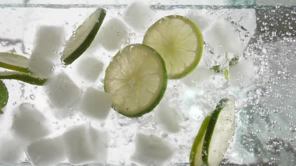 lime slices with ice and mint leaves are poured with a stream of water