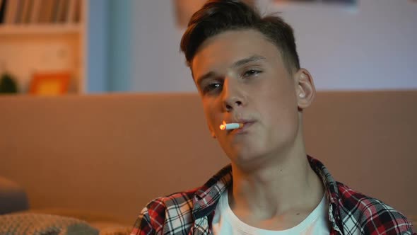 Teenager Boy Sitting Home and Smoking Cigarette, Harmful Unhealthy Habit, Cancer