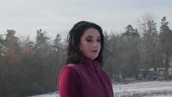 Young Brunette Woman Rides a Beautiful Black Horse on a Field or Snowcovered Farm in Winter