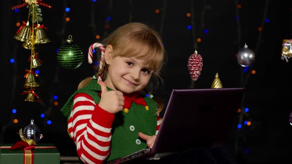 Kid Girl in Christmas Elf Costume Doing Shopping Online Using Laptop Browsing on Social Media