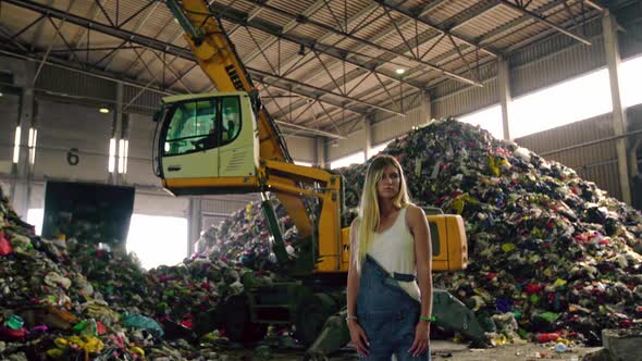 Epic Shot Young Woman in Jeans Standing Against Operating Excavator Against Huge Pile of Trash