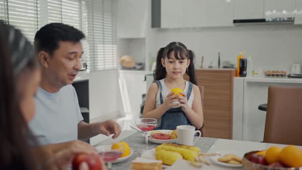  Cheerful young asian parents and cute small kids enjoy breakfast together 