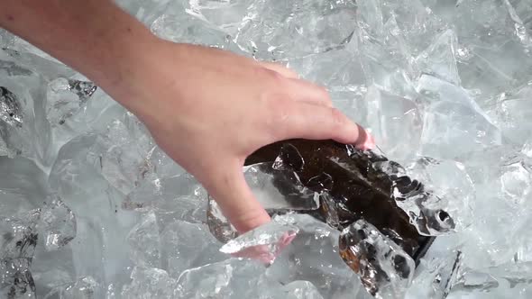 Bottle of Beer Is Pulled By a Man's Hand. White Background. Slow Motion