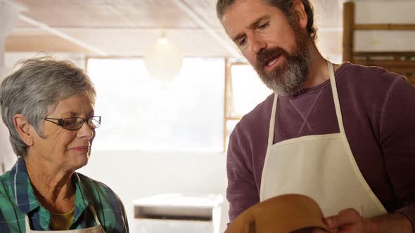 Male and female potter interacting while examining a pot