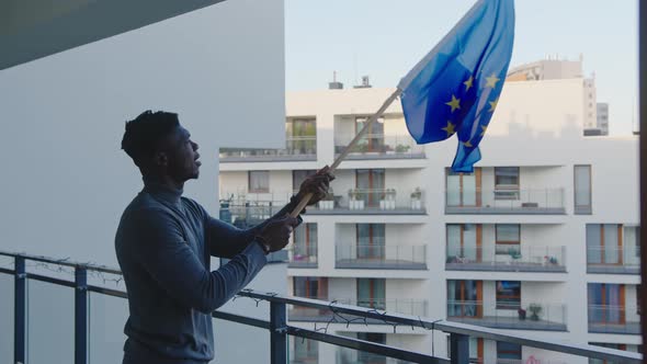 Young Black Man Asylum Seeker Waving European Union Flag From the Balcony