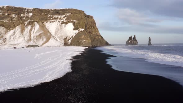 Low Flight Over the Black Sand Beach of Southern Iceland Covered in Snow