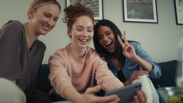 Three best caucasian friends having fun while taking selfie on the sofa. Shot with RED helium camera