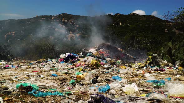 Landfill pile of plastic trash garbage waste burning in rubbish dump, toxic smoke air pollution rele
