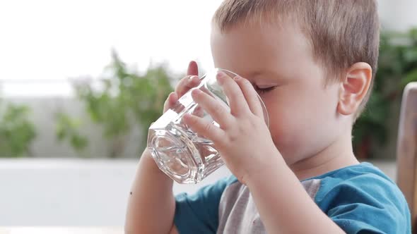 Cute Baby Boy Drinking a Glass of Water in a Cafe. Slow Motion Little Boy Drinking Water. Close-up