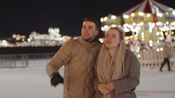 Young Couple Walking at Christmas Celebration Outdoors