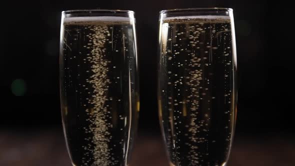 Two Glasses of Sparkling Wine on a Black Background with Blurred Flashing Lights
