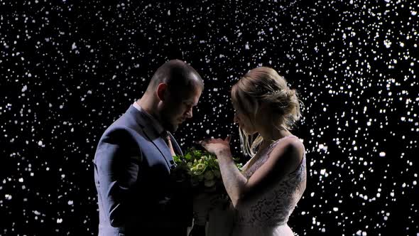 Lovely Couple Against the Background of Falling Snow. A Man in a Suit and a Pretty Woman in a White