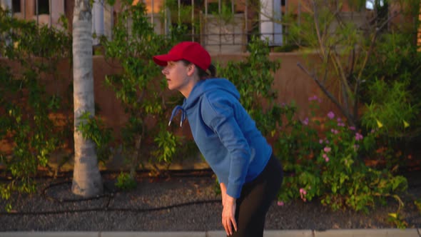 Woman Tying Shoelaces and Starts Jogging Along the Street Among the Tropical Alley