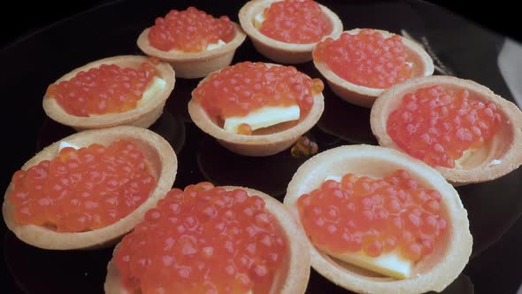 Red Caviar Is Put with a Spoon on Tartlets. Preparation of Snacks with Red Caviar. Top View