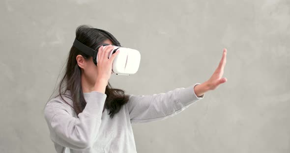 Woman playing VR device over gray background 