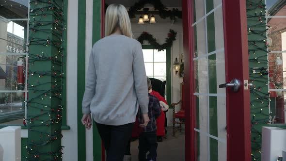 Family walking in holiday booth to sit on santa's lap