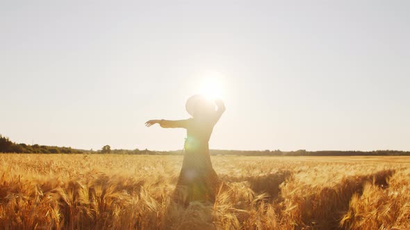 Pregnant woman in the rays of the sunset in the field