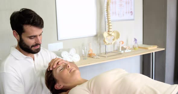 Physiotherapist giving head massage to a female patient