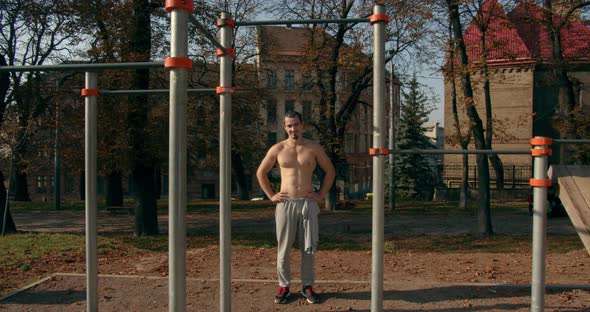 Young Man Is Standing Near Horizontal Bars After Training in Sunny Weather 