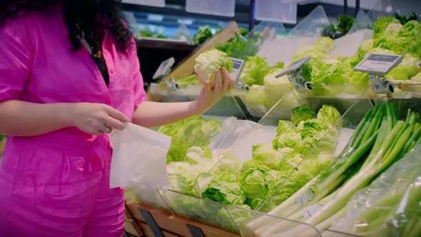 Attractive Young Woman in a Pink Suit Chooses Cabbage Salad Makes Purchases in the Supermarket Buys