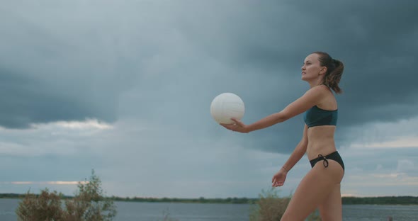 Young Sportswoman Dressed Bikini Is Playing Beach Volleyball, Medium Shot Against Picturesque Cloudy