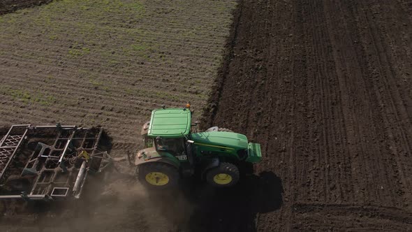 Tractor plows the ground with a plow in the field