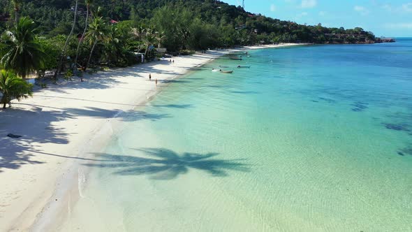 Beautiful above clean view of a white paradise beach and blue ocean background in vibrant 4K