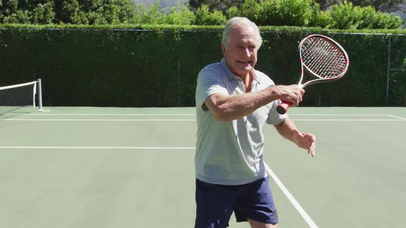 Caucasian senior man with racket shadow practicing tennis on the tennis court