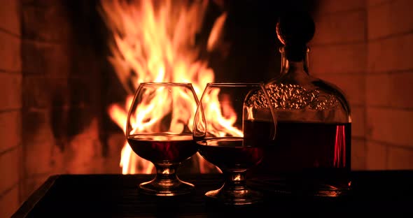 Two Glasses of Cognac and a Bottle Near the Fireplace