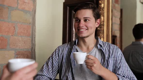 Young Man Drinking Coffee With Woman At Cafe