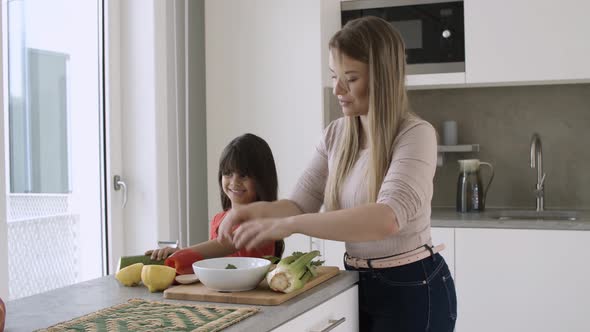 Girl Helping Her Mom To Cook Salad for Dinner