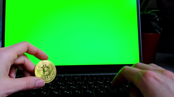 A bitcoin gold coin in hand on a laptop on the background of a laptop monitor with a green chromakey