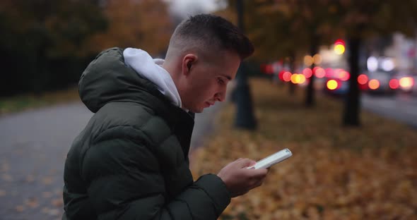 Portrait of Man Using Smartphone Sitting in the Autumn City