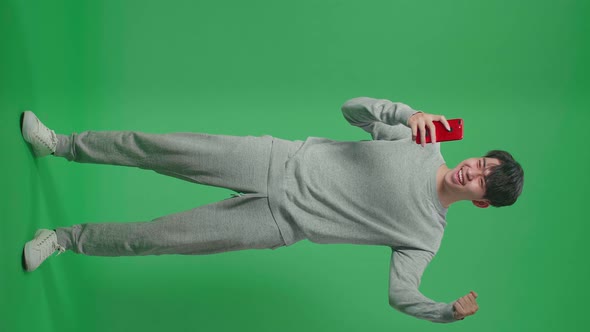 Full Body Of Asian Man Celebrating While Using Mobile Phone In The Green Screen Studio