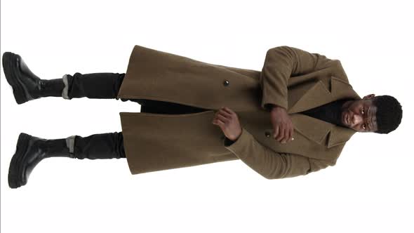 Handsome Young AfroAmerican Man Rubs Sleeves of the Brown Coat White Background Isolated Full Shot