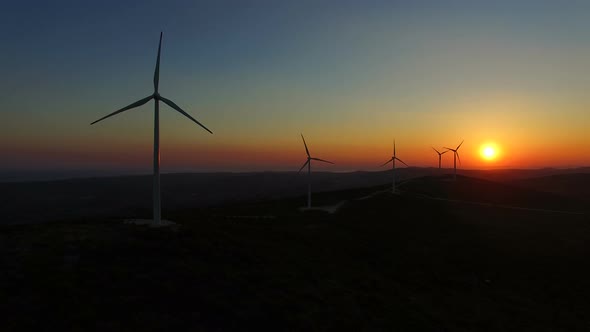 Sun setting behind elegant windmills on a hill