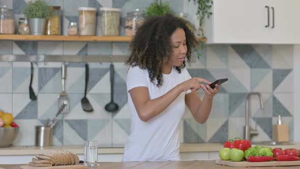 African Woman Taking Picture of Fruits on Smartphone in Kitchen