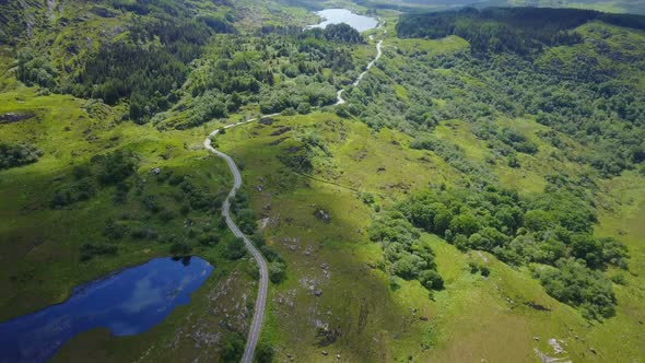 Amazing high aerial video of reflective blue lake in foreground with long winding road,shadow of mov