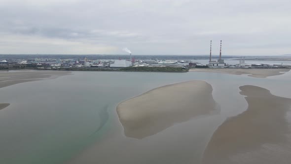 Pale Sandymount strand shores distant from Poolbeg stacks aerial